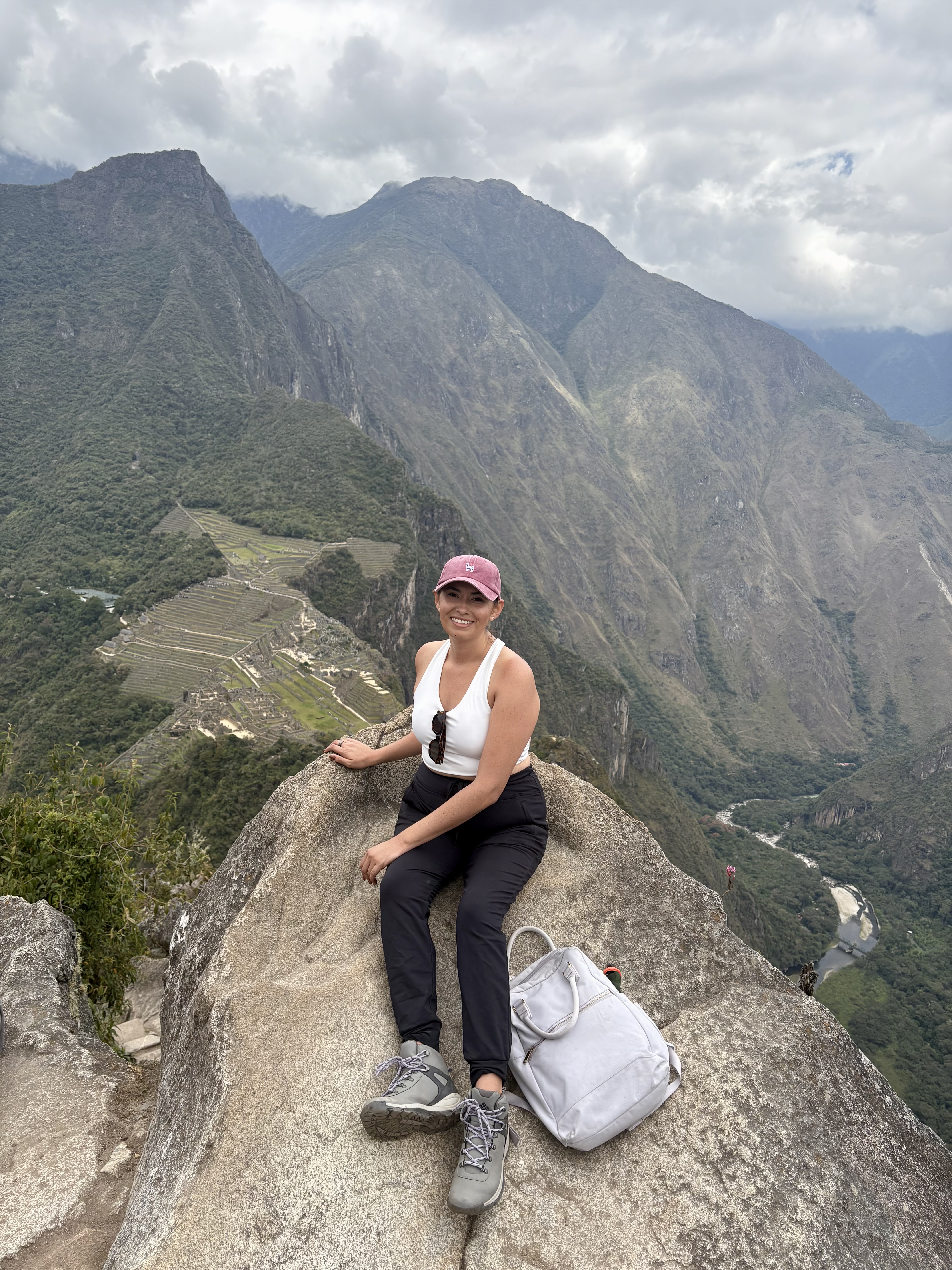 Marissa sitting on a boulder overlooking Machupicchu constructions below